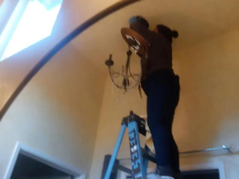 Electrician installing a chandelier in a Argo residence
